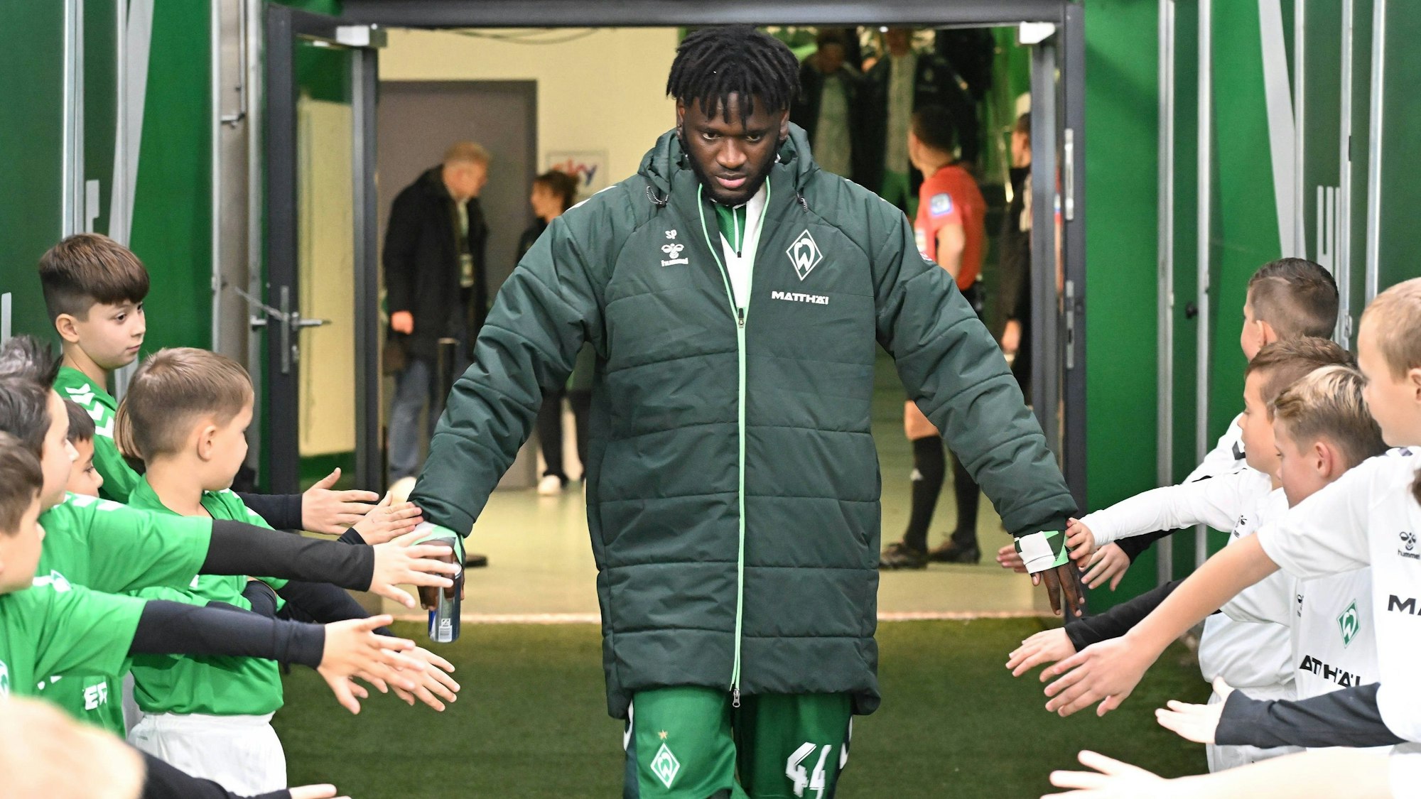 Victor Boniface klatscht mit Einlaufkindern von Werder Bremen ab.