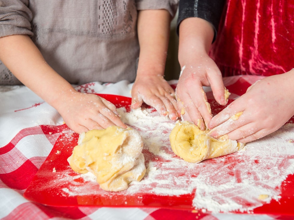 Zwei Mädchen kneten rohen Teig