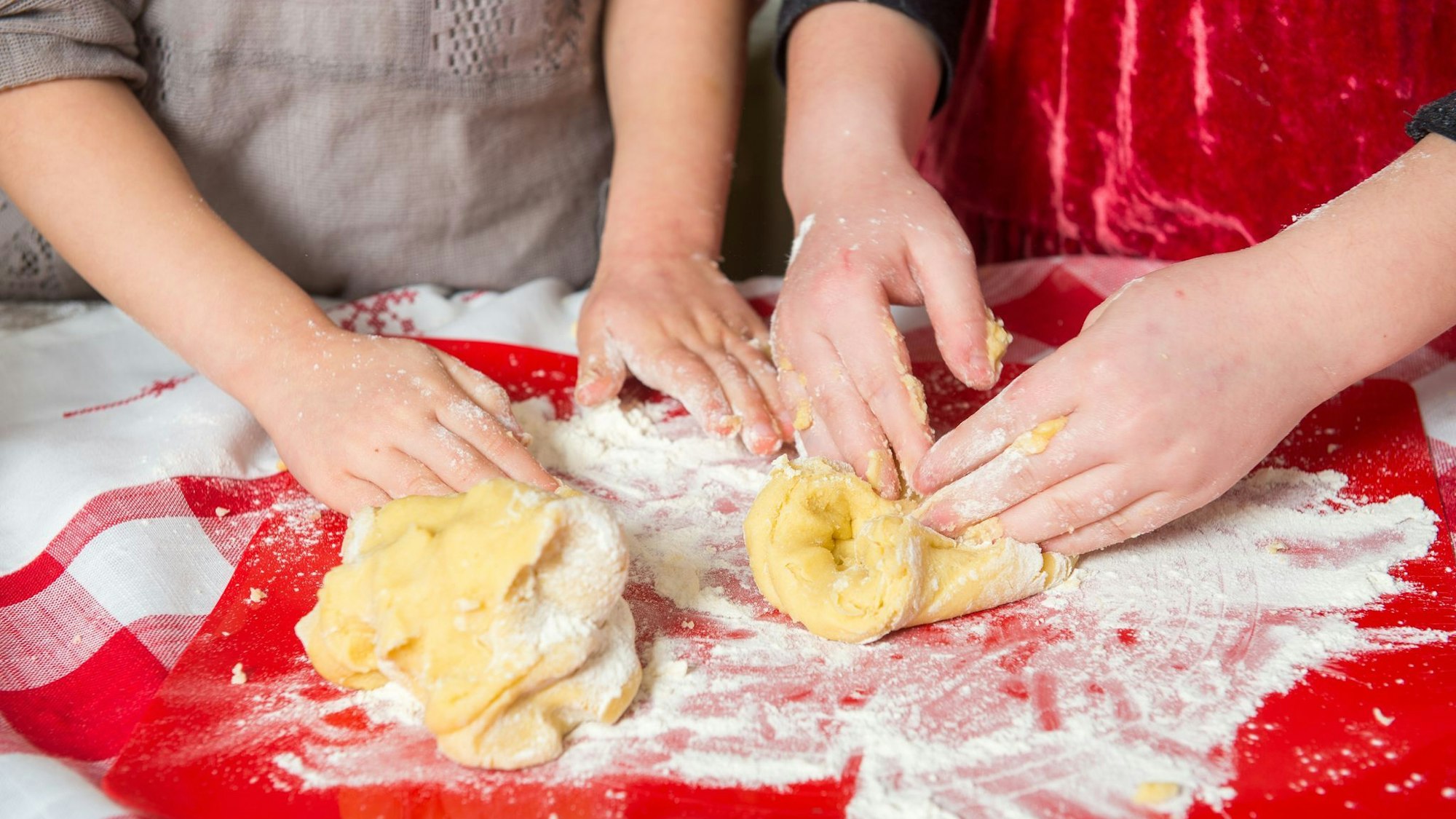 Zwei Mädchen kneten rohen Teig