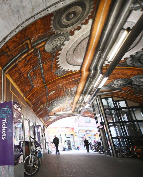 Ein Bahntunnel ist beschmiert und beklebt, auch ein dort stehender Ticketautomat ist mit Graffiti besprüht.