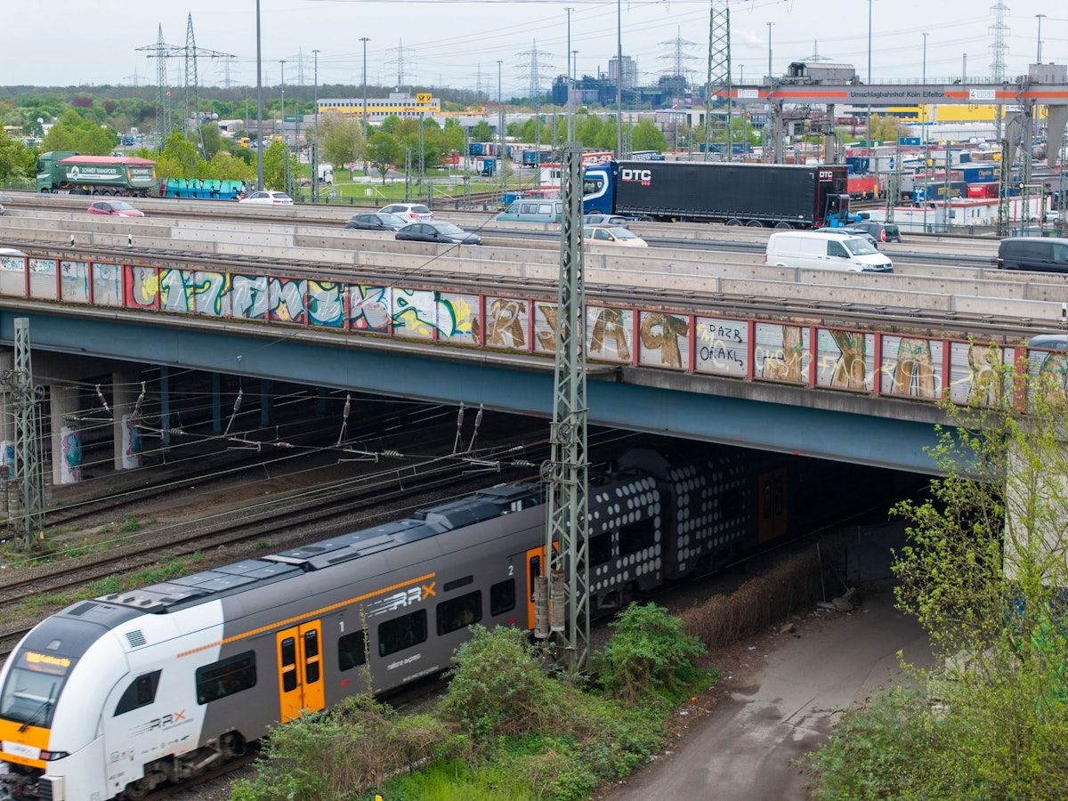 Ein Zug fährt unter einer Brücke durch.