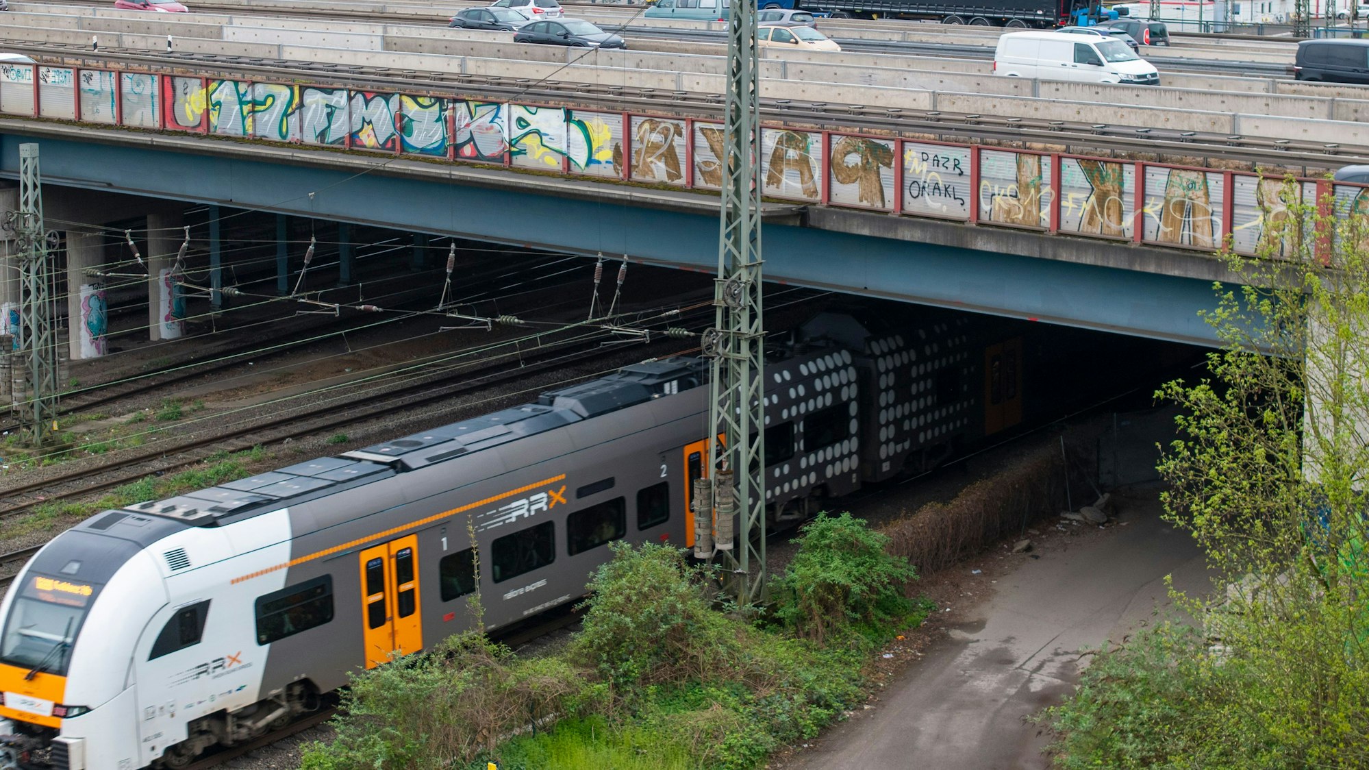 Ein Zug fährt unter einer Brücke durch.