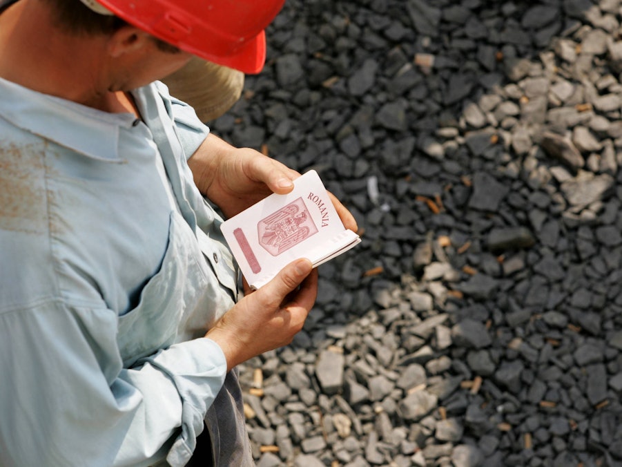 Mann mit Helm, Reisepass auf Schotter