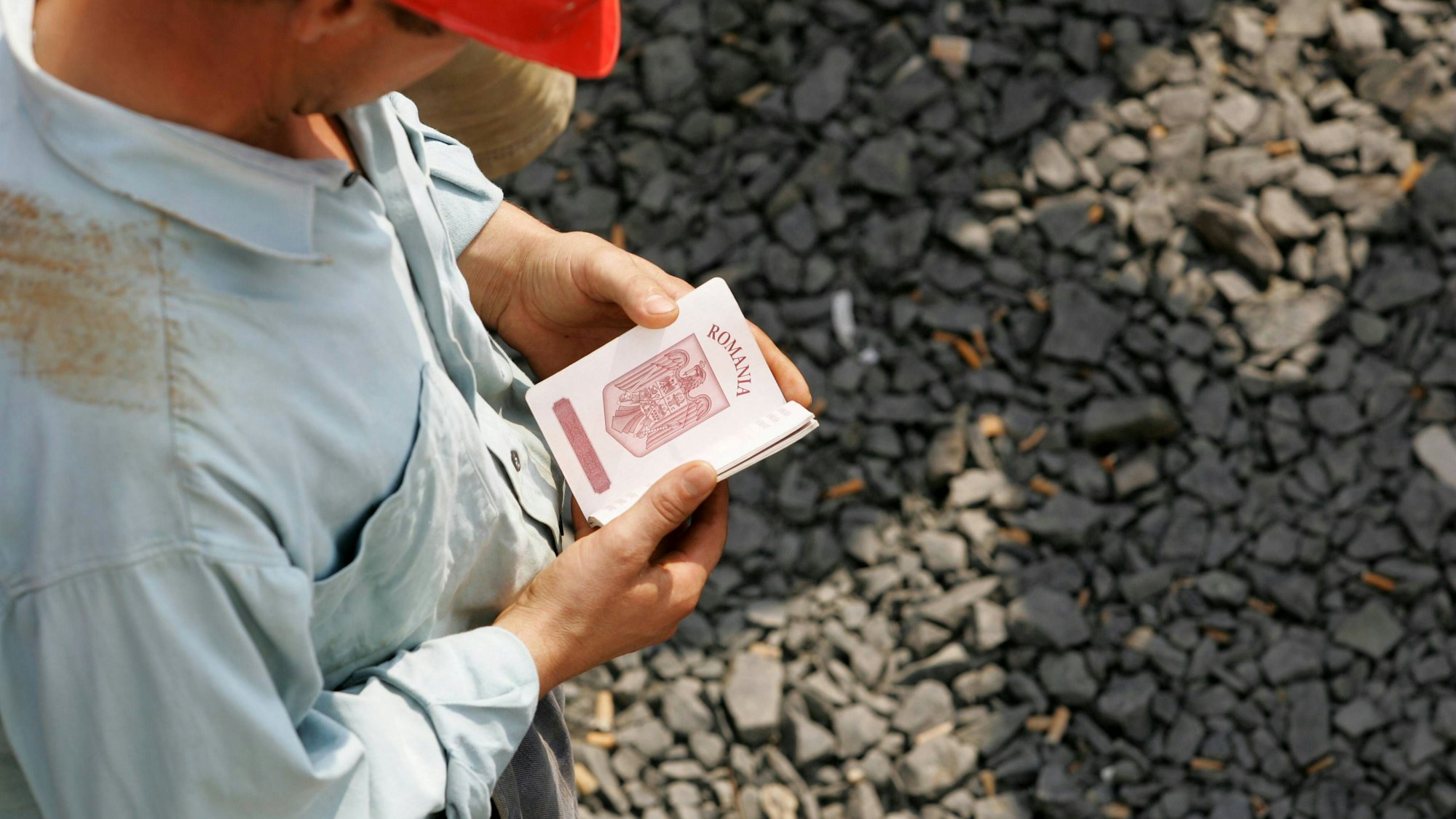 Mann mit Helm, Reisepass auf Schotter