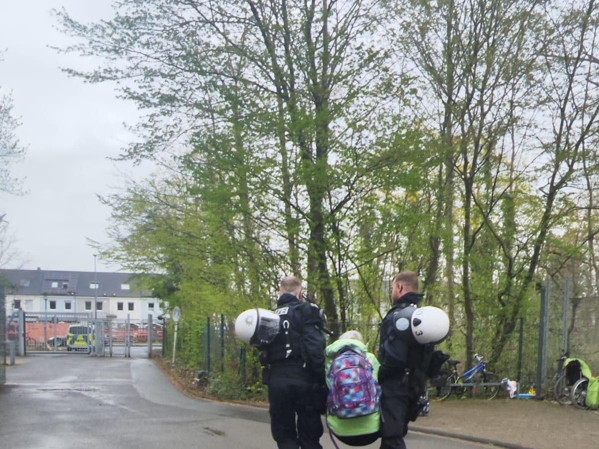 Zwei Polizisten tragen eine Person weg.