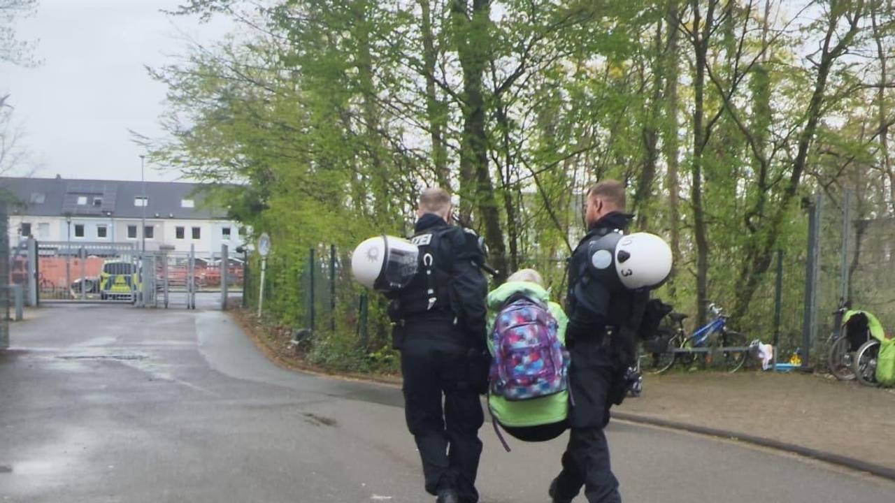 Zwei Polizisten tragen eine Person weg.