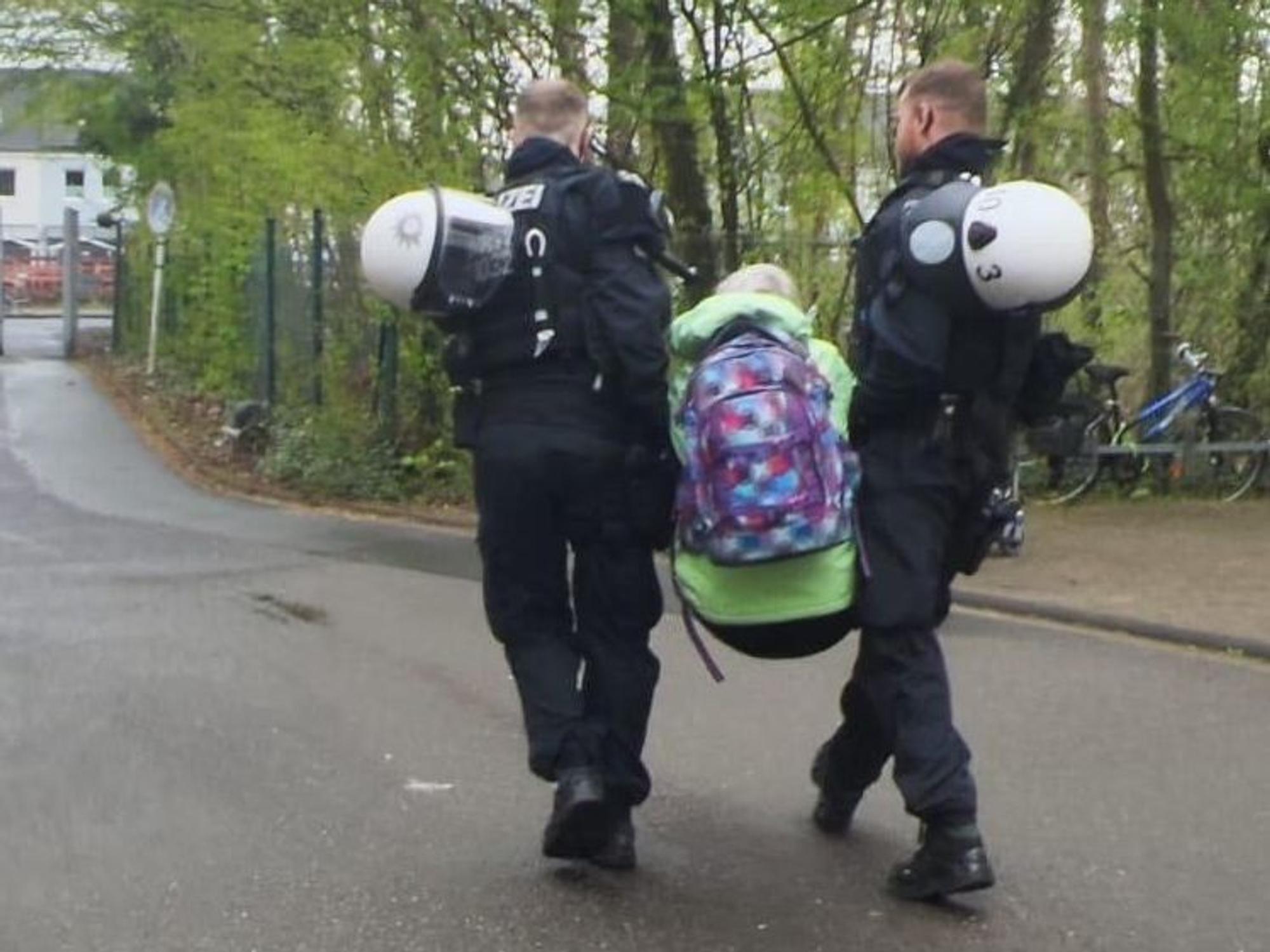 Zwei Polizisten tragen eine Person weg.