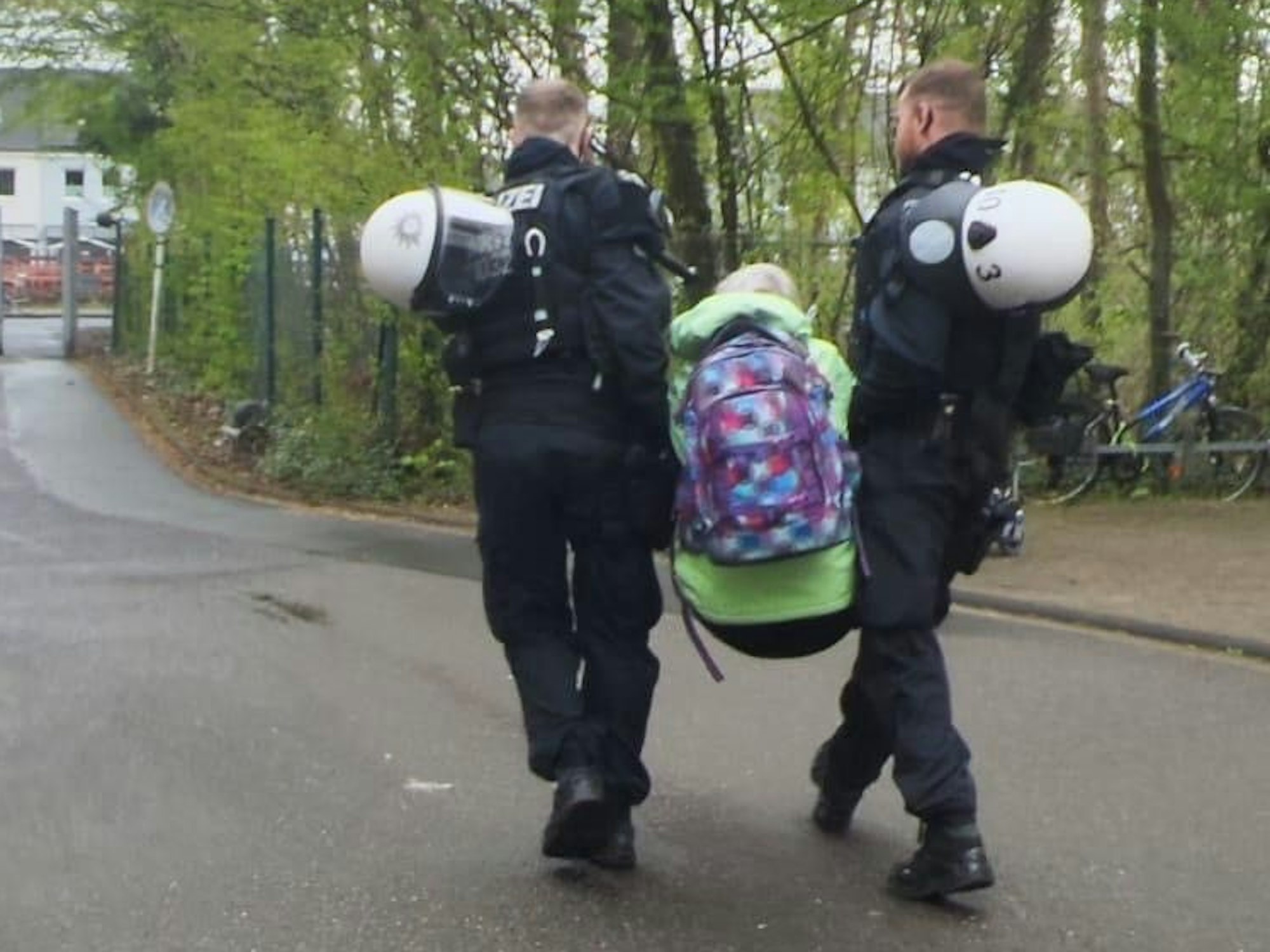 Zwei Polizisten tragen eine Person weg.