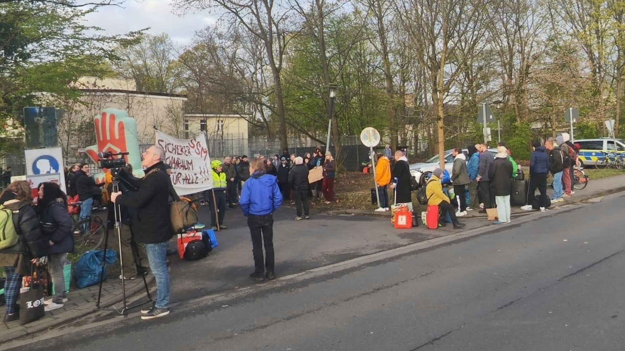 Mehrere Menschen stehen mit Protestplakaten vor einem Gebäude.