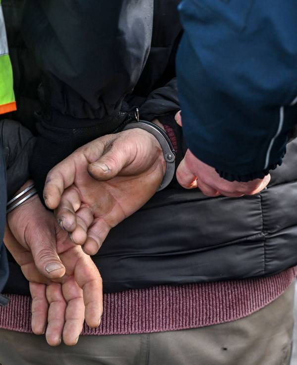 Polizisten legen einem Mann Handschellen an