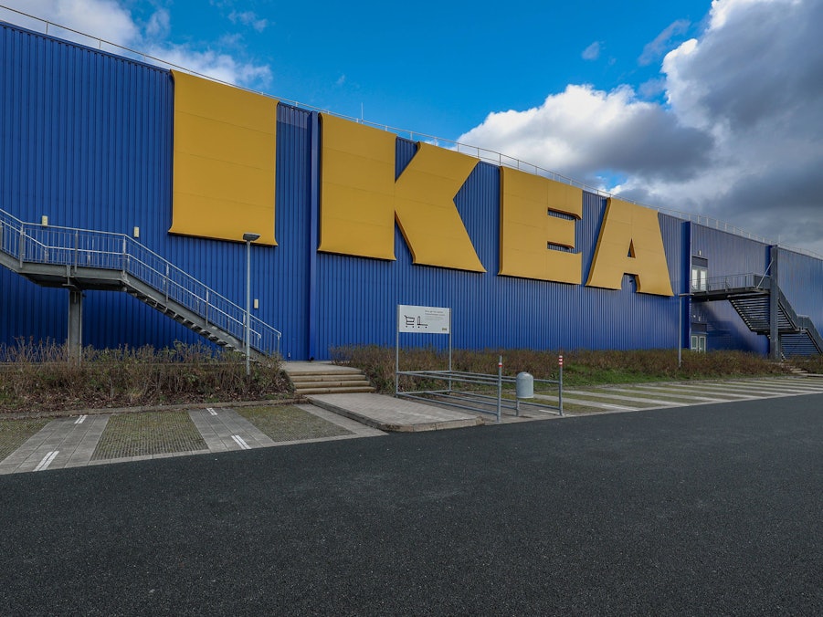 Gebäudefassade mit großen Buchstaben, Treppen und Parkplatz