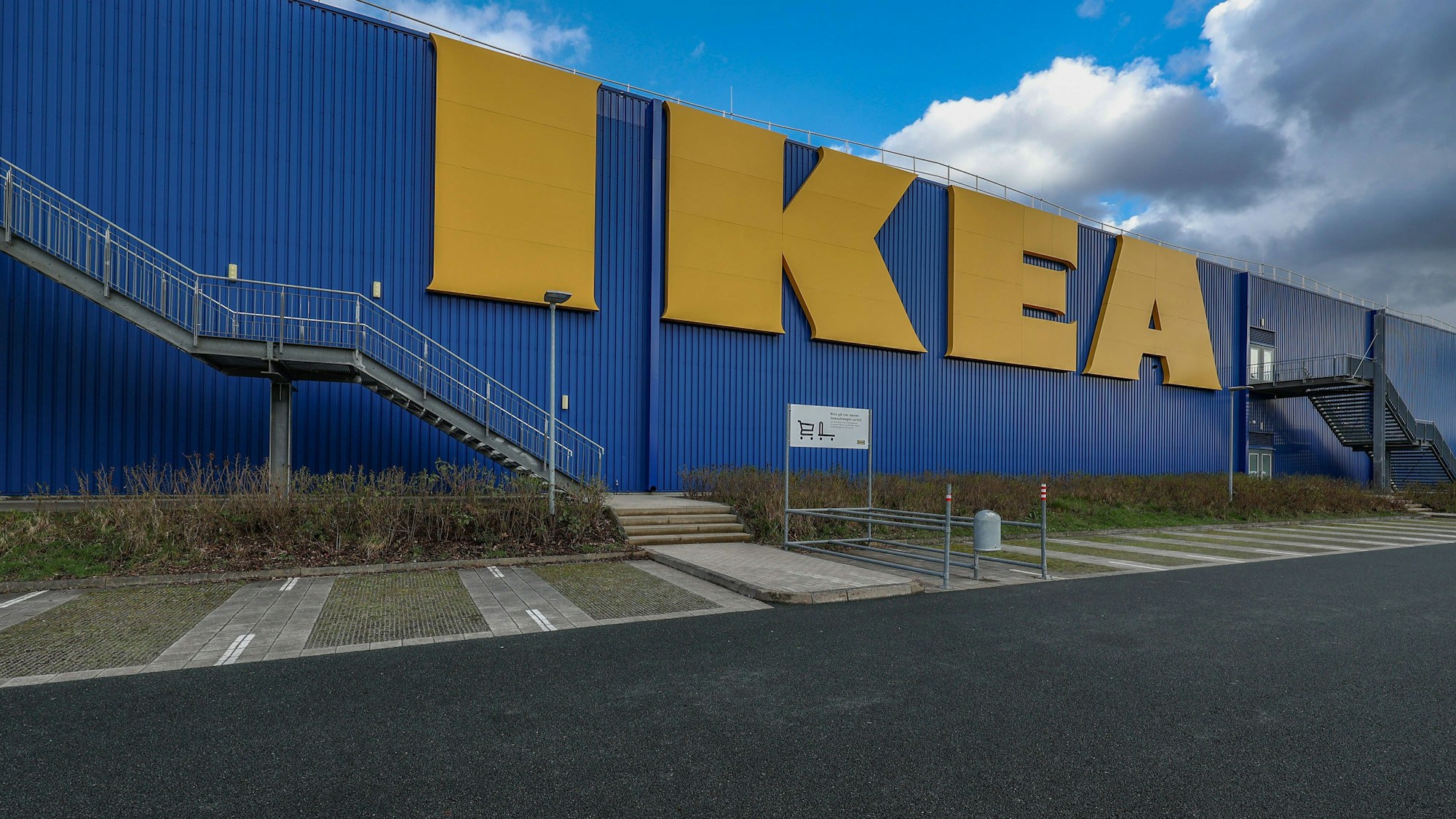 Gebäudefassade mit großen Buchstaben, Treppen und Parkplatz