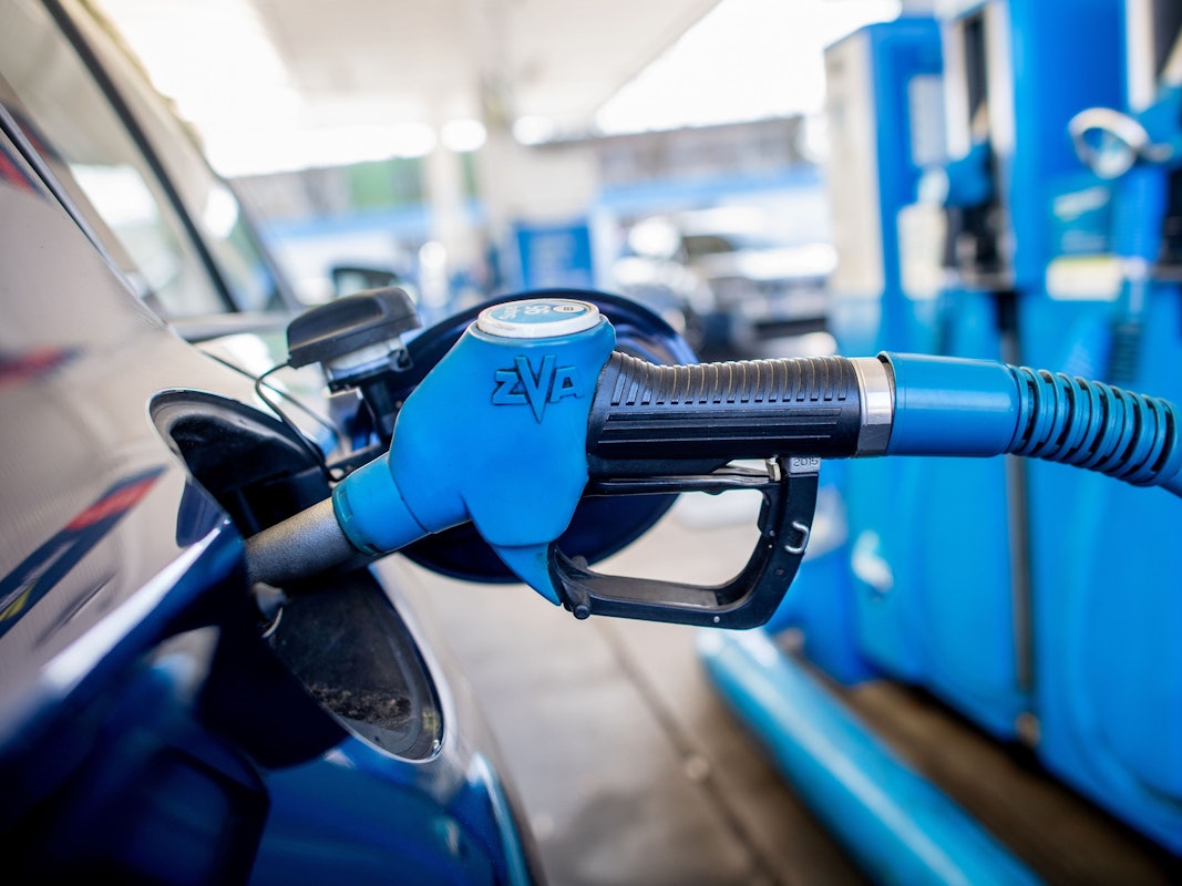 Eine Zapfpistole mit der Aufschrift „Super 95“ steckt an einer Tankstelle in der Tanköffnung eines Fahrzeugs.