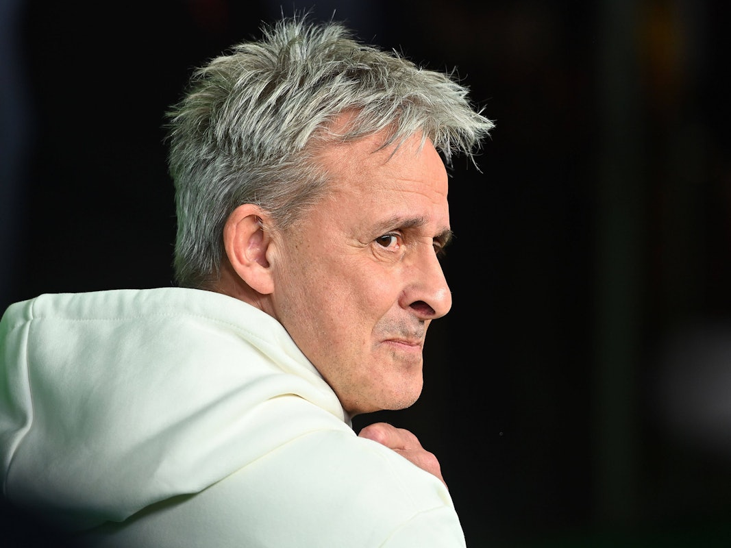 Pierre Littbarski schaut im Hoodie über seine rechte Schulter.