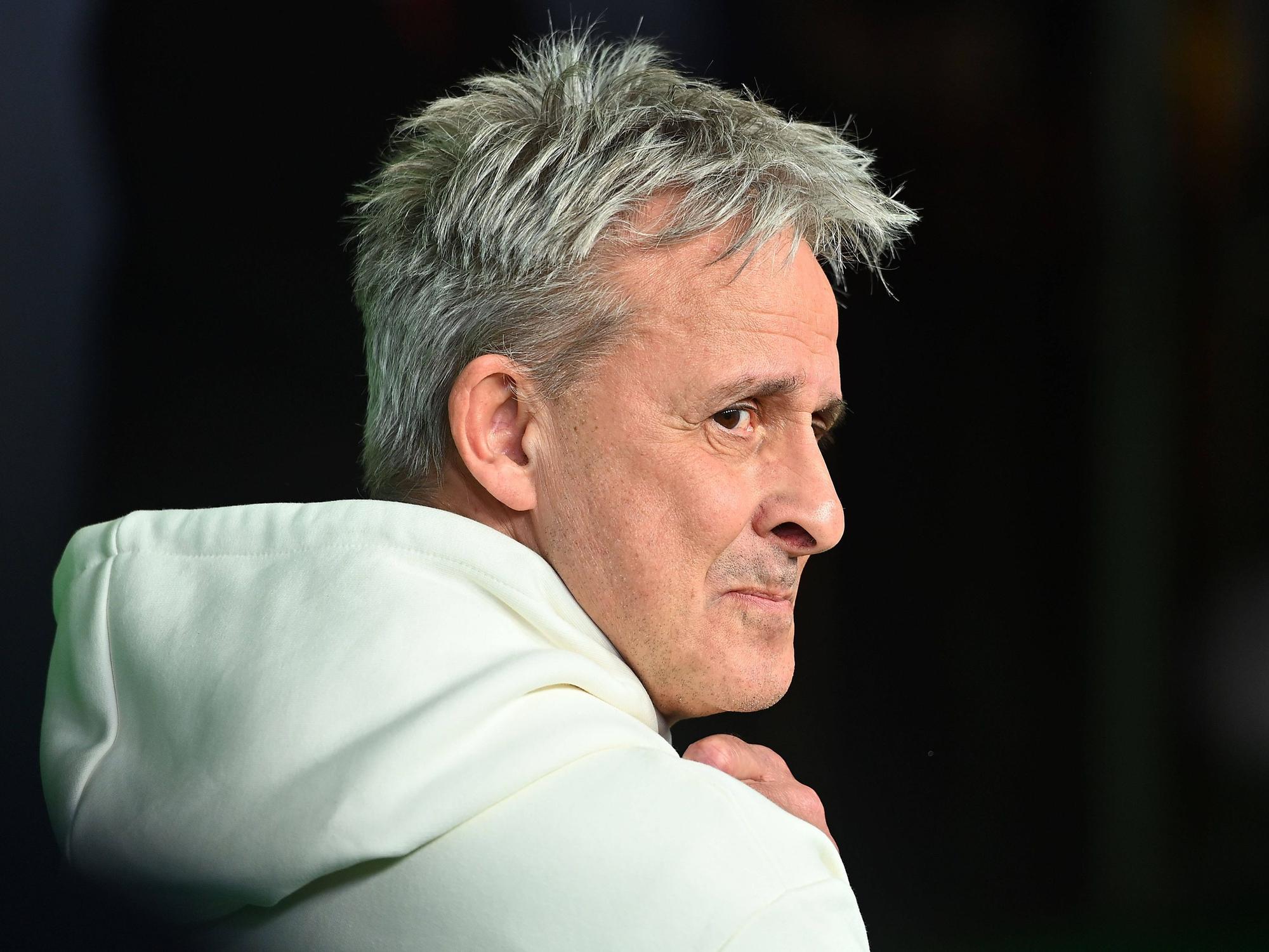 Pierre Littbarski schaut im Hoodie über seine rechte Schulter.
