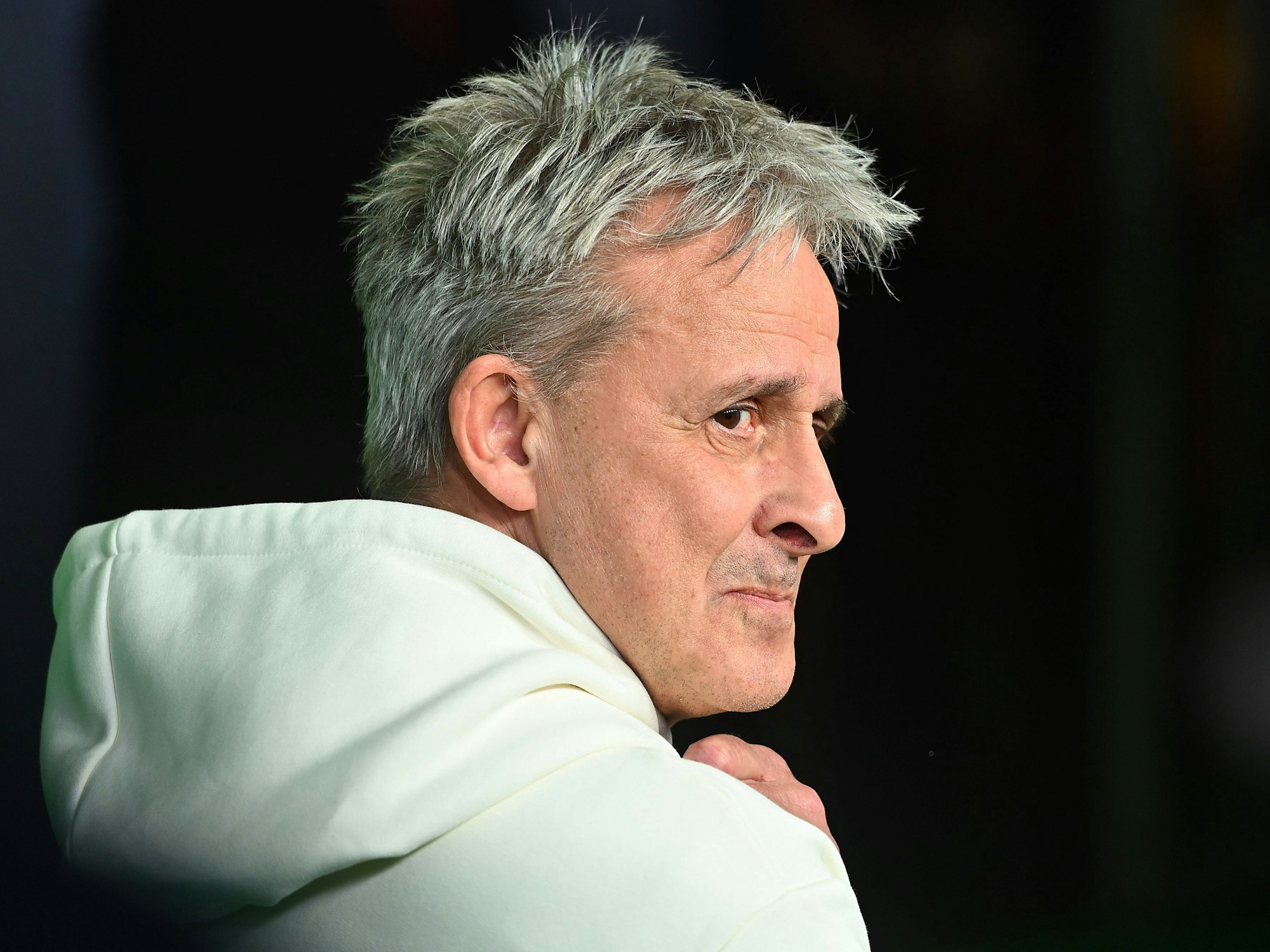 Pierre Littbarski schaut im Hoodie über seine rechte Schulter.