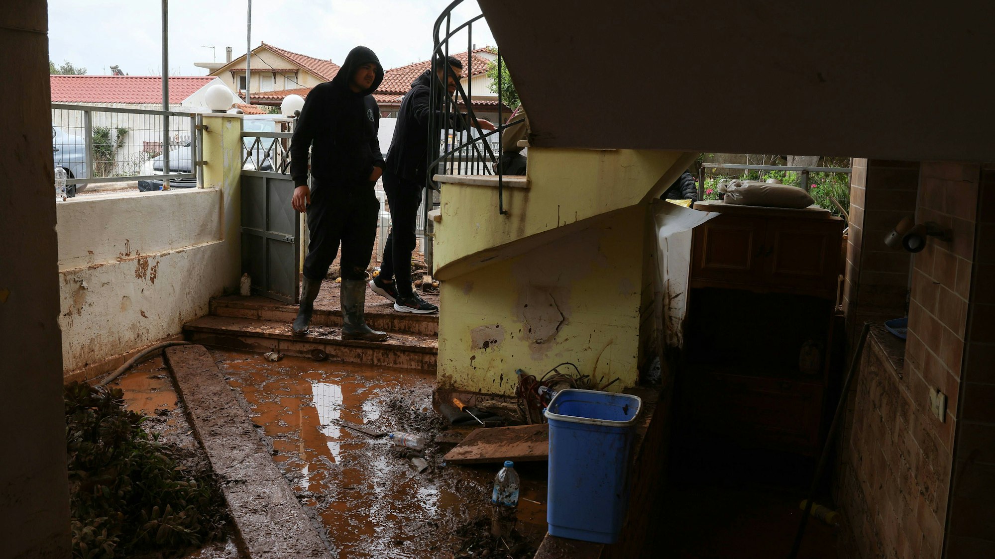 Männer in schlammiger Umgebung nach Überschwemmung