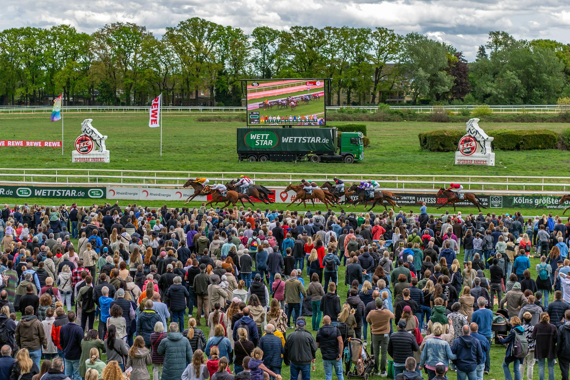 Zuschauer beim FC-Renntag verfolgen das Geschehen auf der Galopprennbahn in Köln-Weidenpesch.