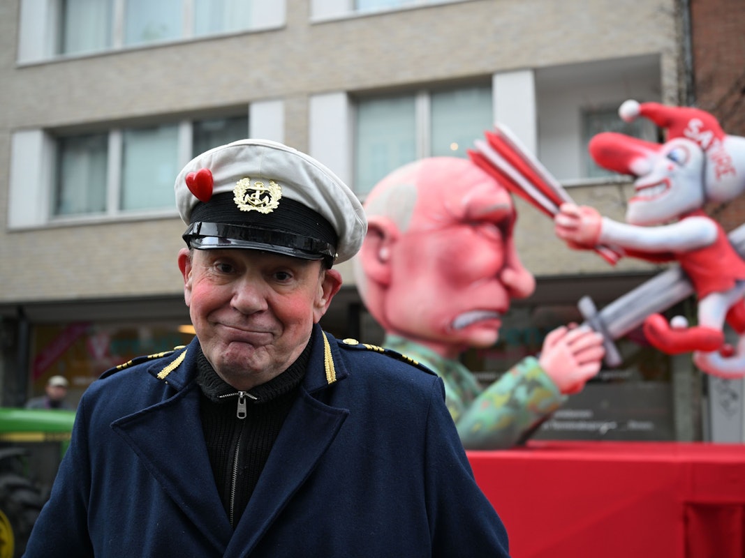 Jacques Tilly steht vor dem Mottowagen auf dem Putin die Düsseldorfer Karnevalsfigur Hoppeditz aufspießt.