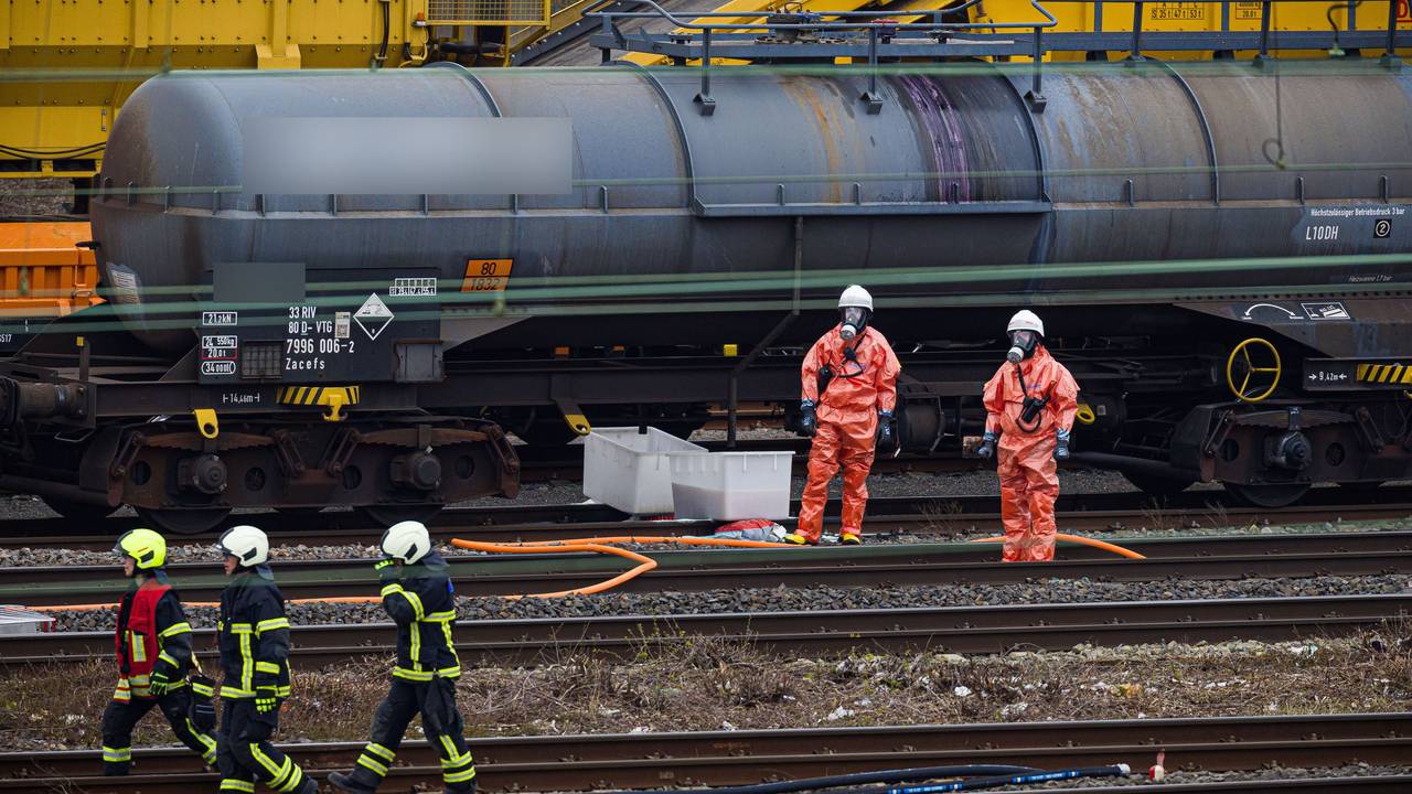 Einsatzkräfte der Feuerwehr stehen vor einem Kesselwagen am Bahnhof.