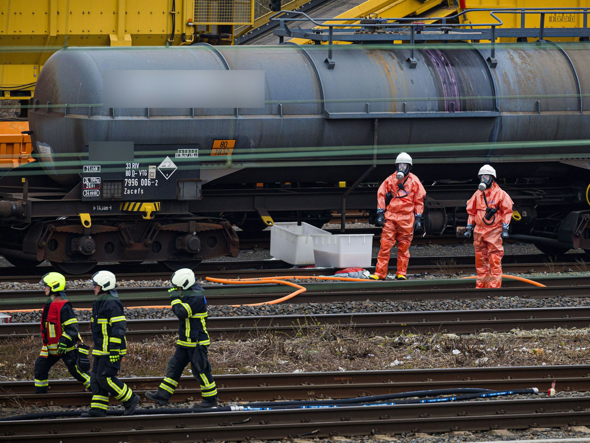 Einsatzkräfte der Feuerwehr stehen vor einem Kesselwagen am Bahnhof.