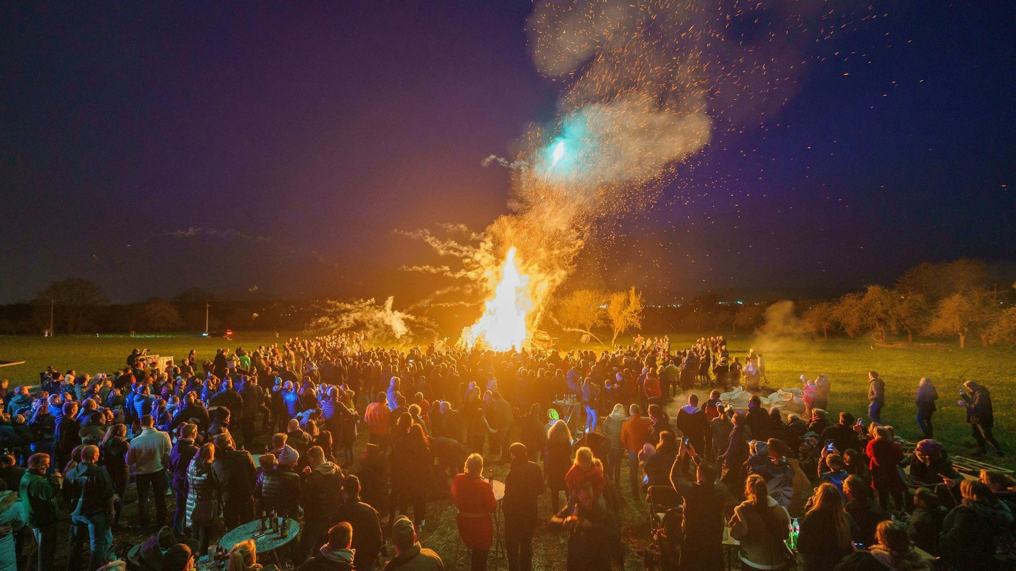 Menschen stehen um ein Osterfeuer