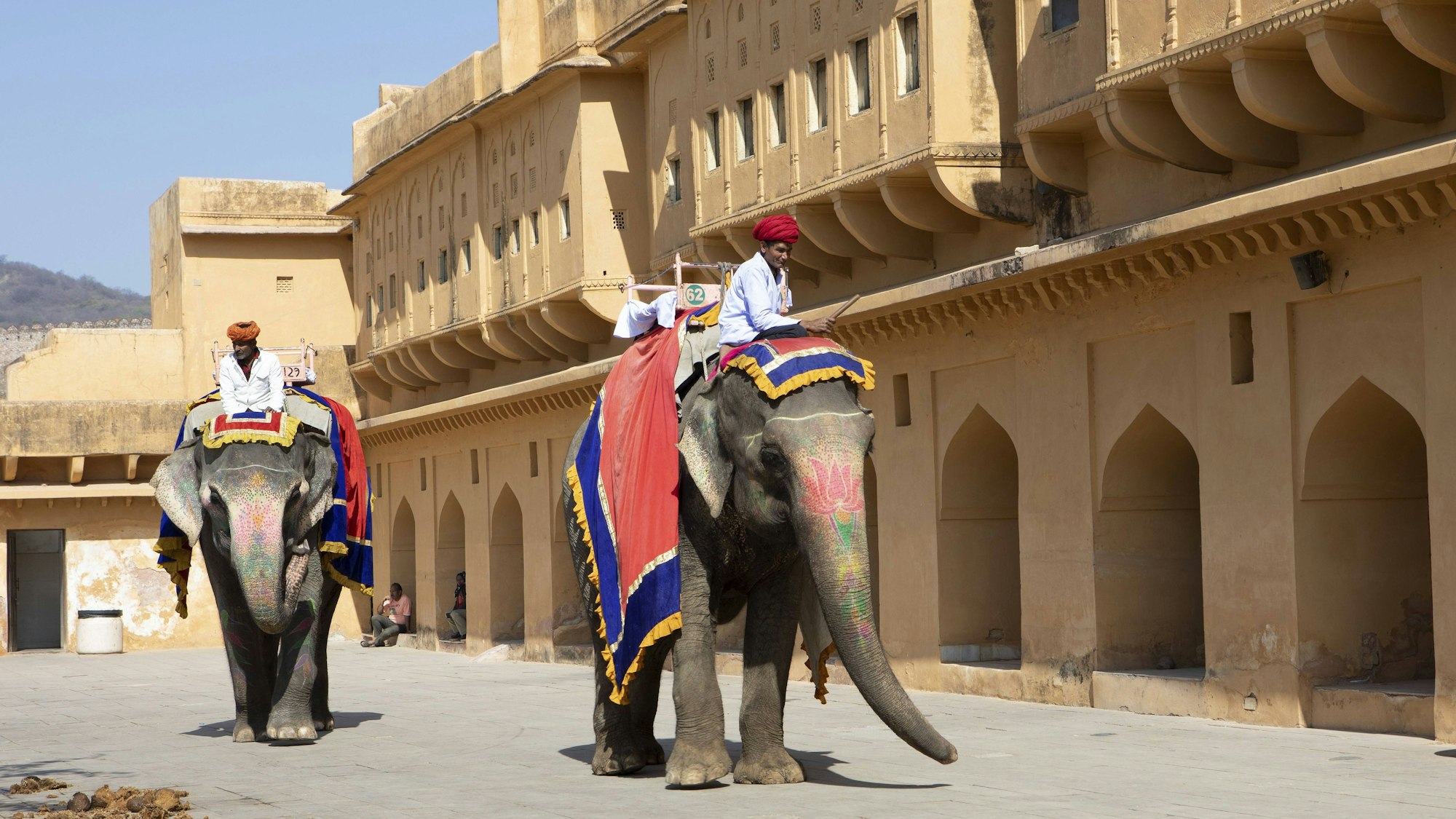 Indische Mahuts auf bemalten Elefanten vor Gebäude