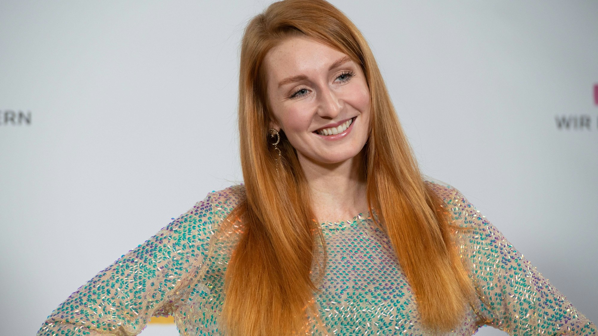 Lena Jensen mit rotem Haar und Pailletten-Oberteil