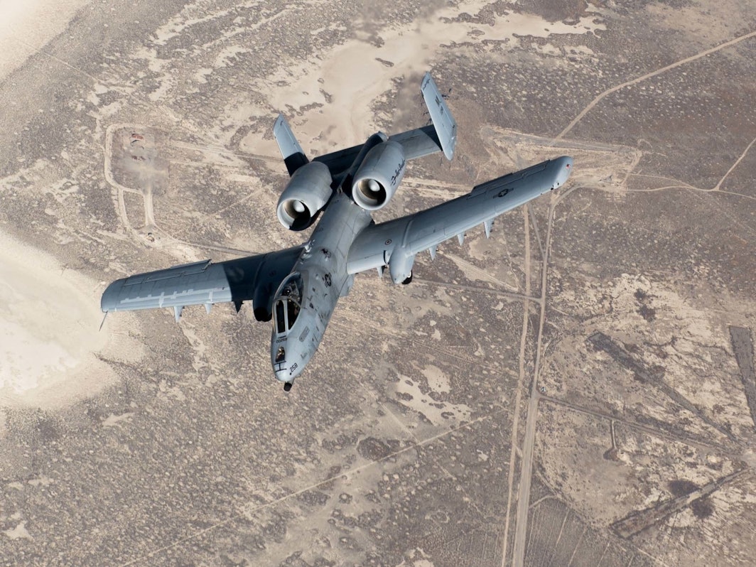 Ein Kampfjet fliegt über unbewohntes Gelände.