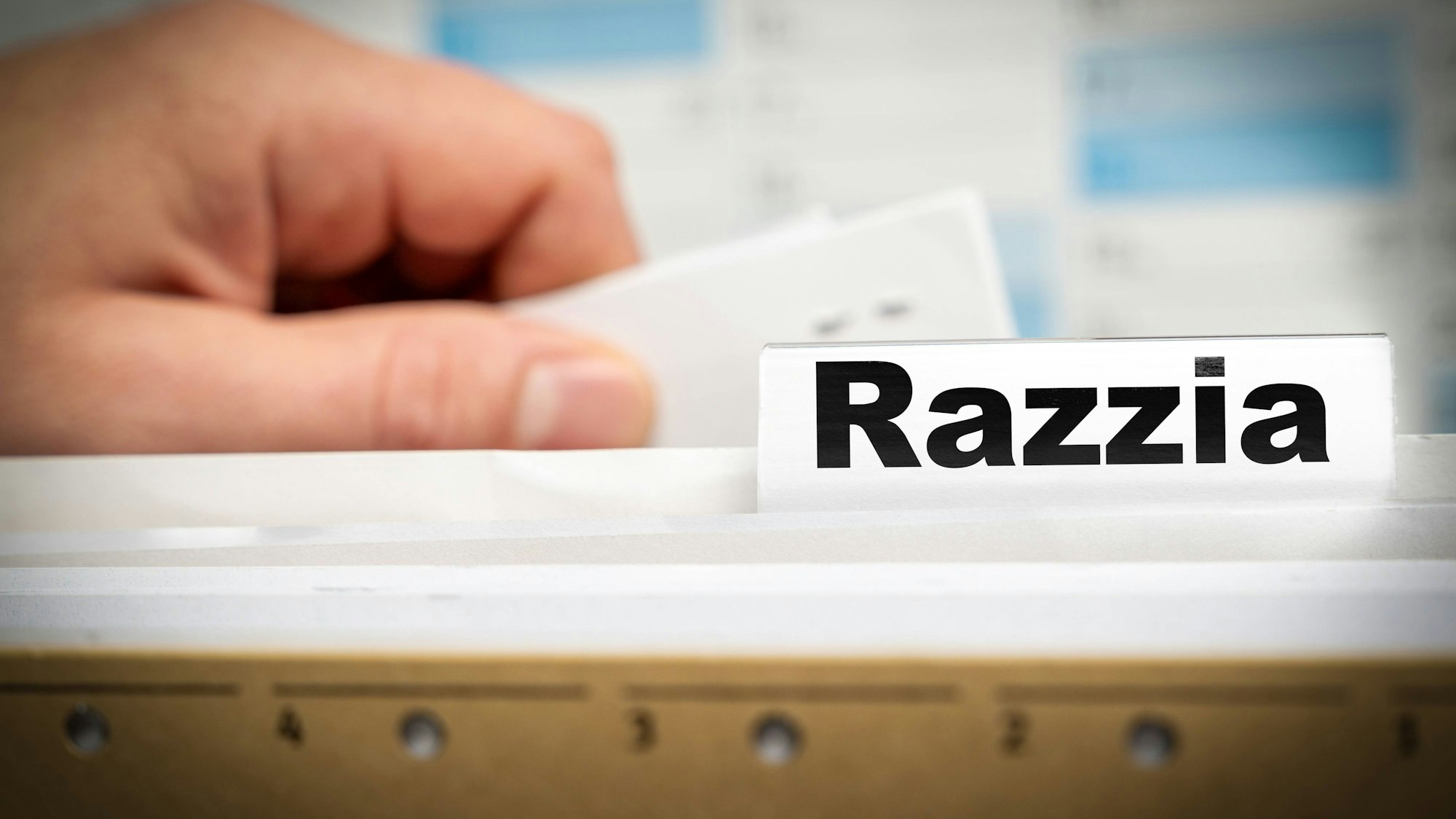 Hand am Karteikasten mit Aufschrift Razzia