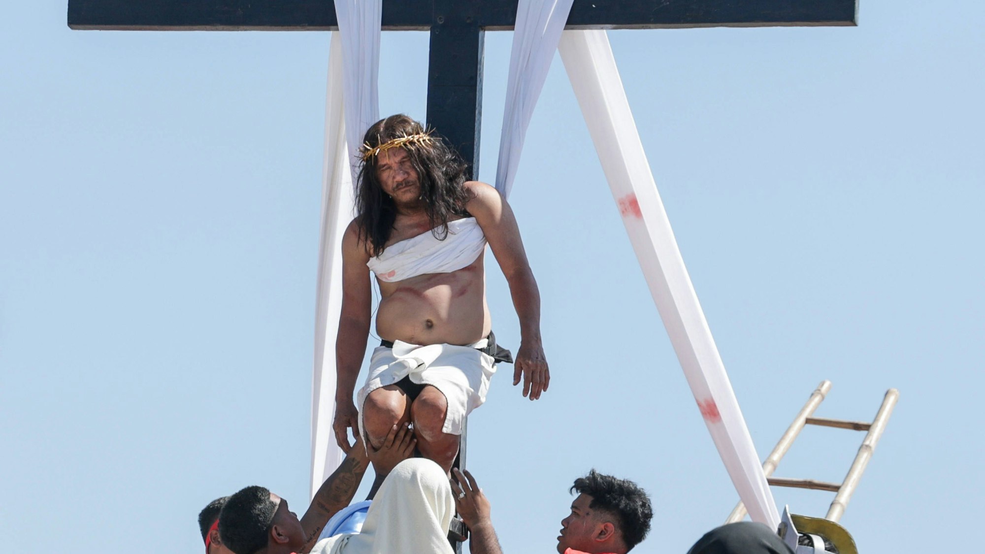 Ruben Enaje als Jesus am Kreuz, umgeben von Menschen