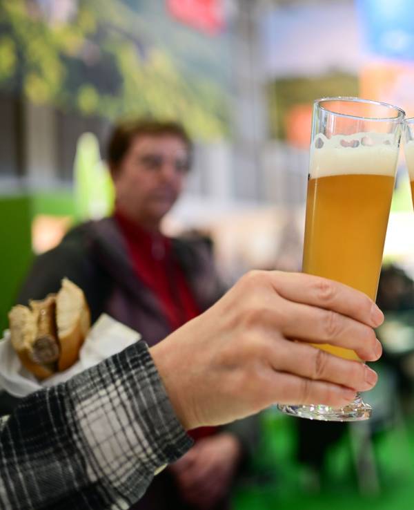 Zwei Personen stoßen mit einem Bier an.