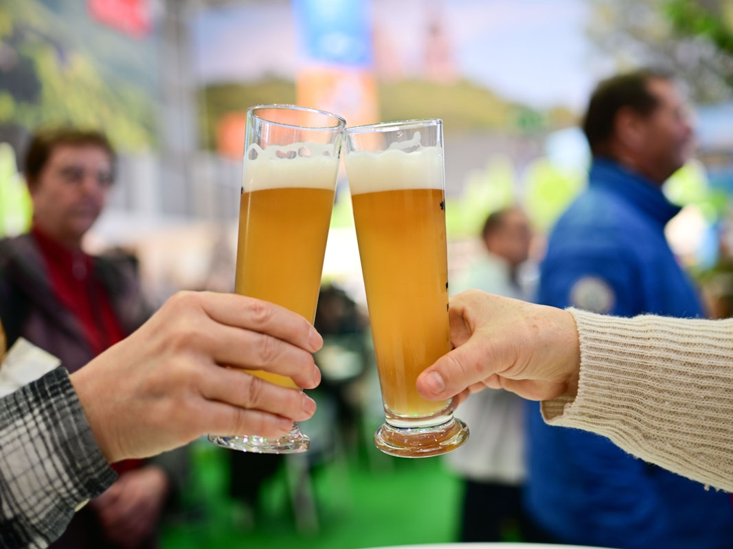 Zwei Personen stoßen mit einem Bier an.