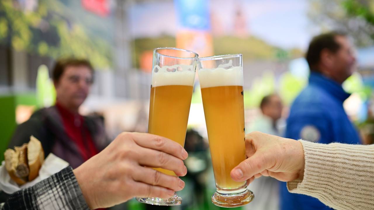 Zwei Personen stoßen mit einem Bier an.