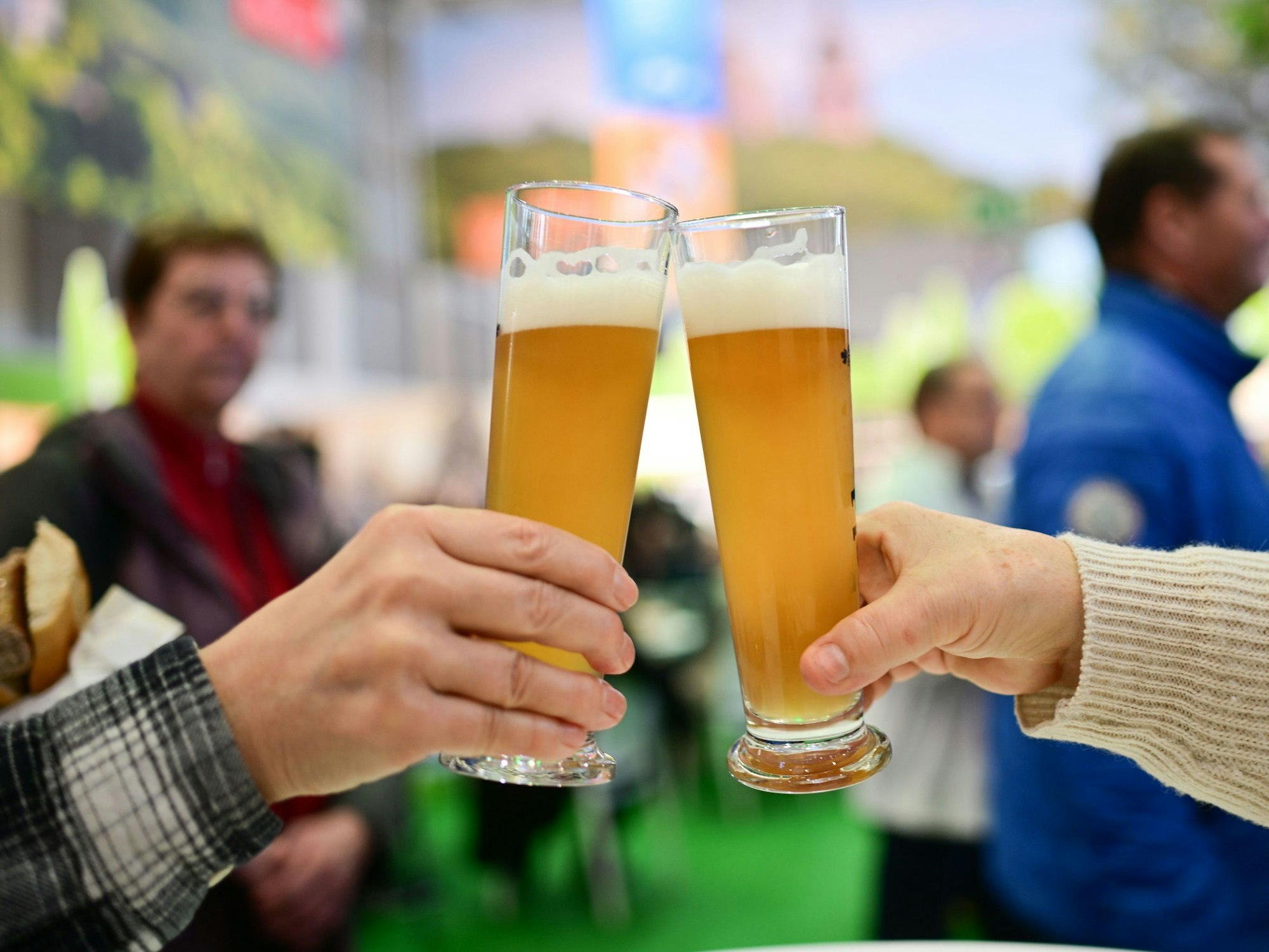 Zwei Personen stoßen mit einem Bier an.