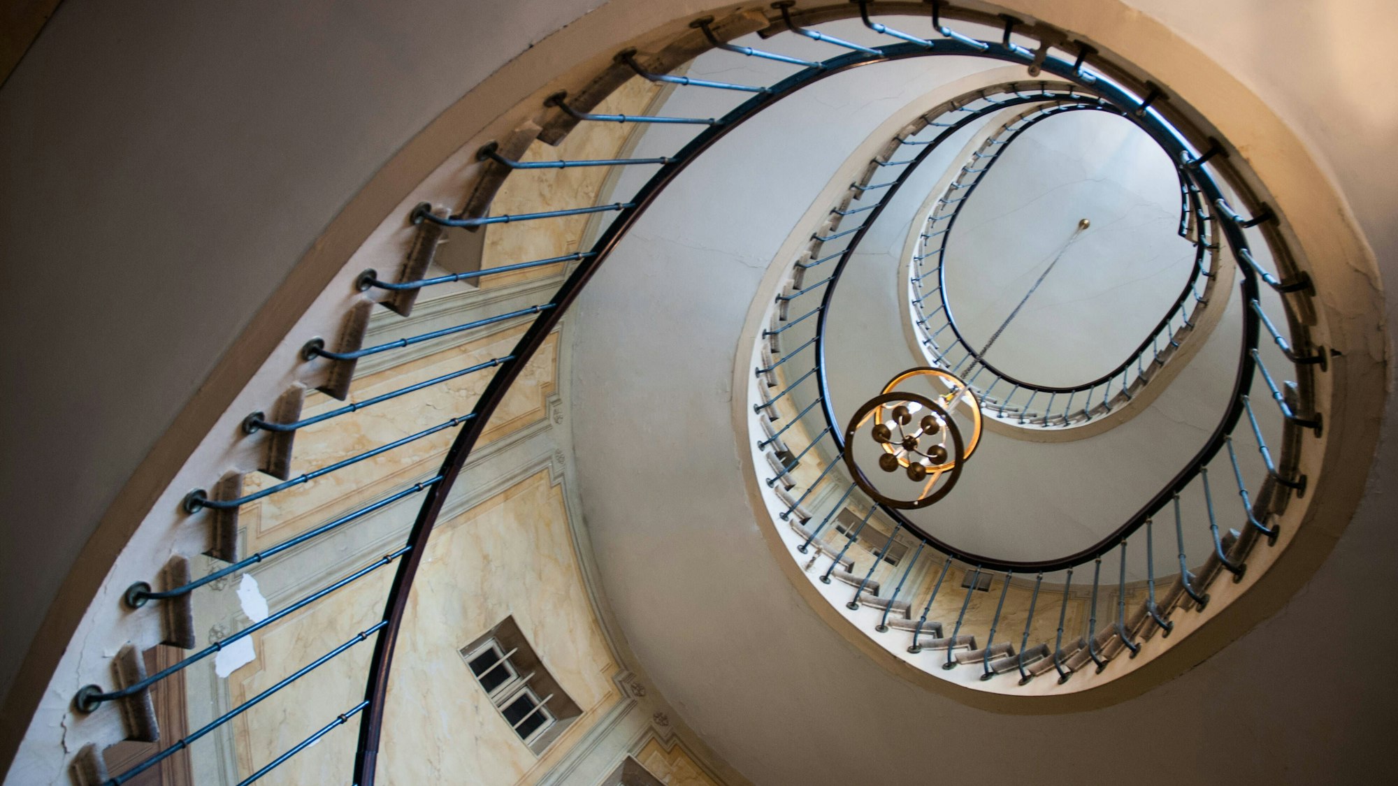 Wendeltreppe mit Leuchter und Fenstern