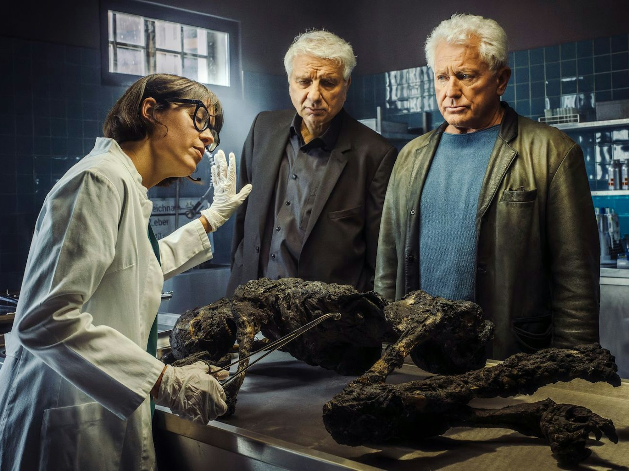 Die Kabarettistin Eva Karl Faltermeier schlüpfte zum „Tatort“-Abschied von Franz Leitmayr (Udo Wachtveitl, Mitte) und Ivo Batic (Miroslav Nemec) in die Gastrolle der Rechtsmedizinerin Dr. Roswitha Schwarz-Fischer. (Bild: BR/NEUESUPER GmbH/Hendrik Heiden)