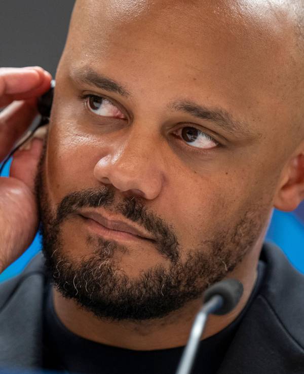 Trainer Vincent Kompany trägt bei einer Pressekonferenz einen Kopfhörer im Ohr.