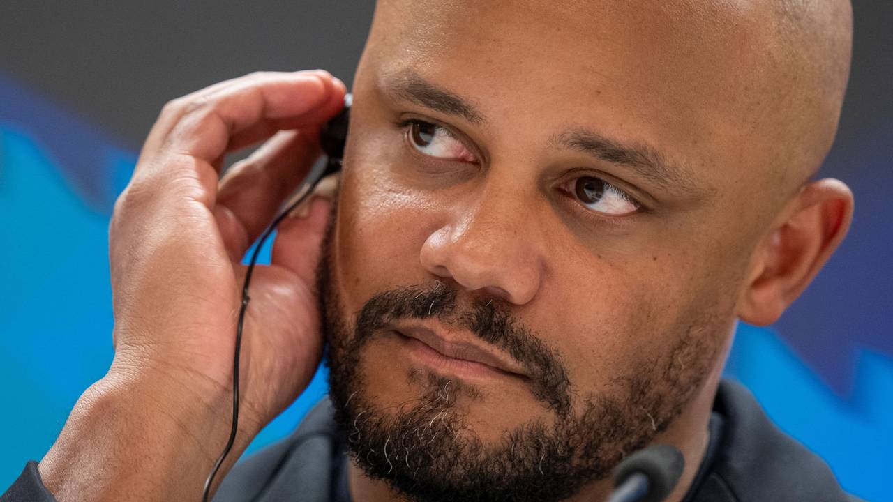 Trainer Vincent Kompany trägt bei einer Pressekonferenz einen Kopfhörer im Ohr.