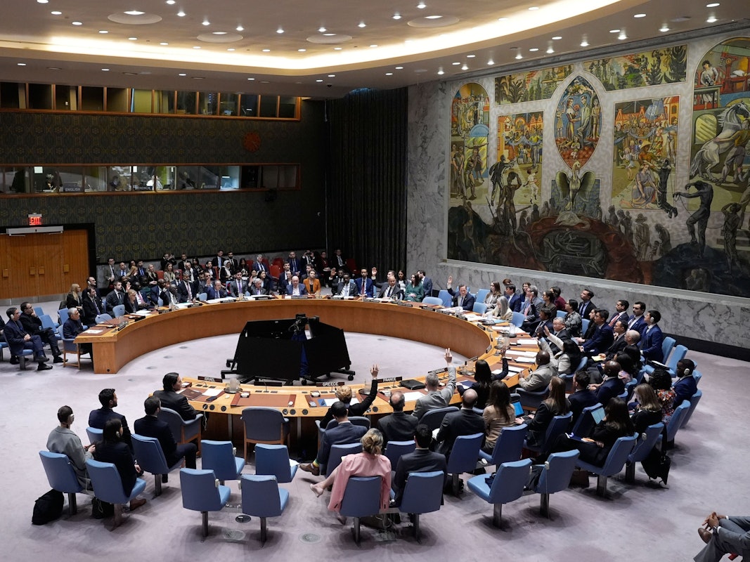 Menschen sitzen um einen halbrunden Tisch herum.