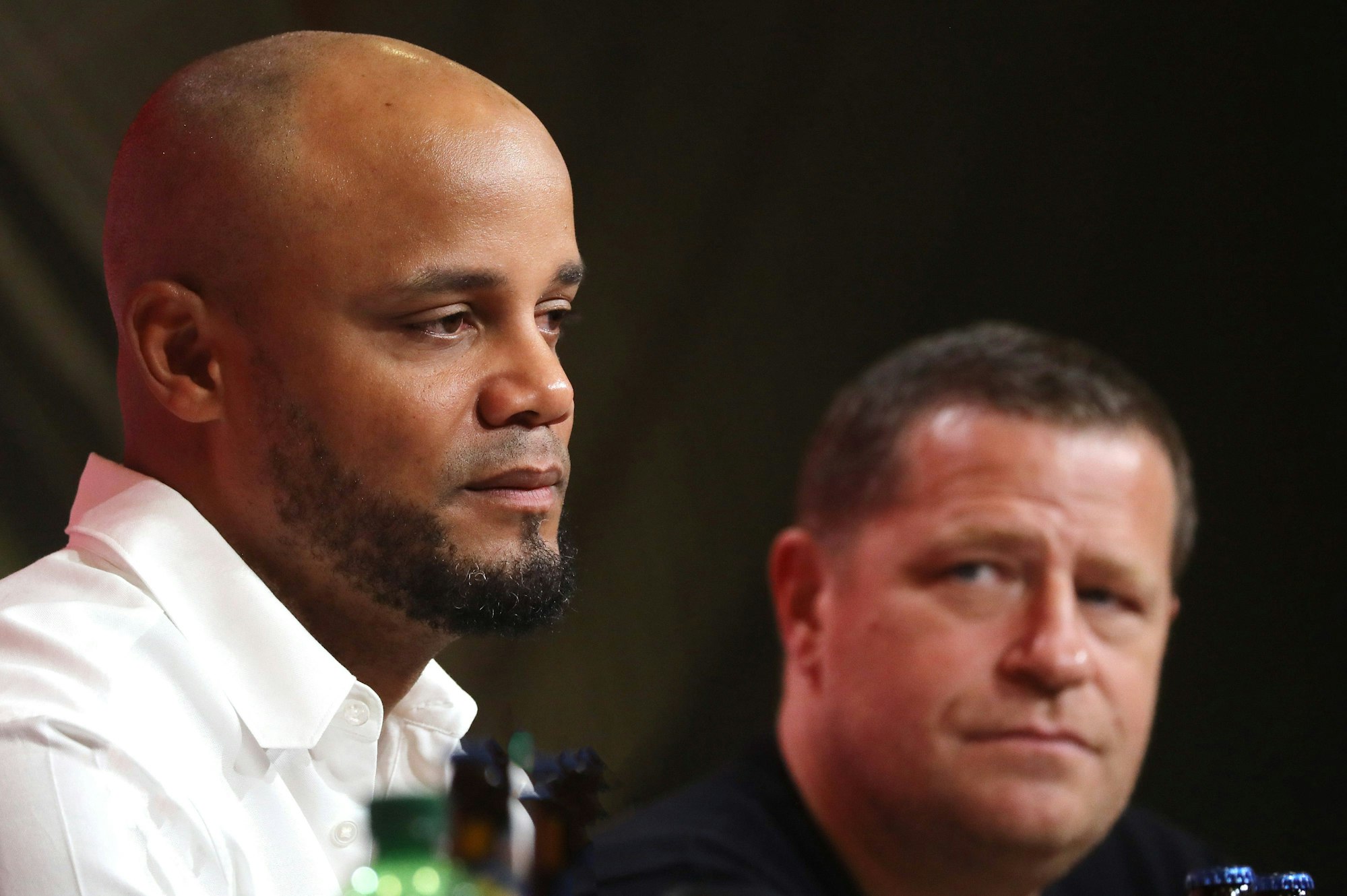 Vincent Kompany bei einer Pressekonferenz. Im Hintergrund sitzt Max Eberl.