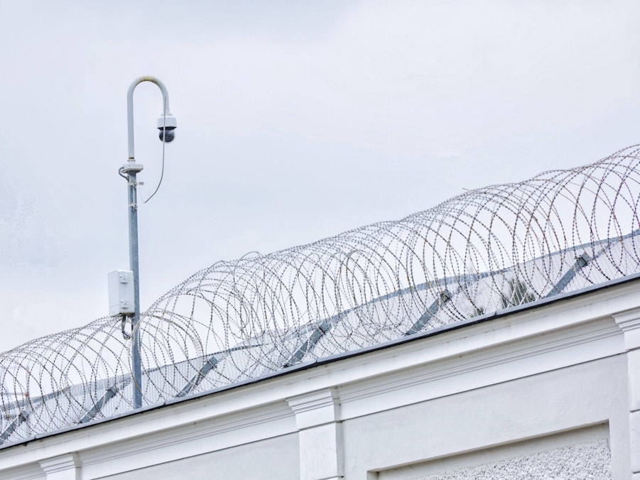 Gefängnismauer mit Stacheldraht und Kamera