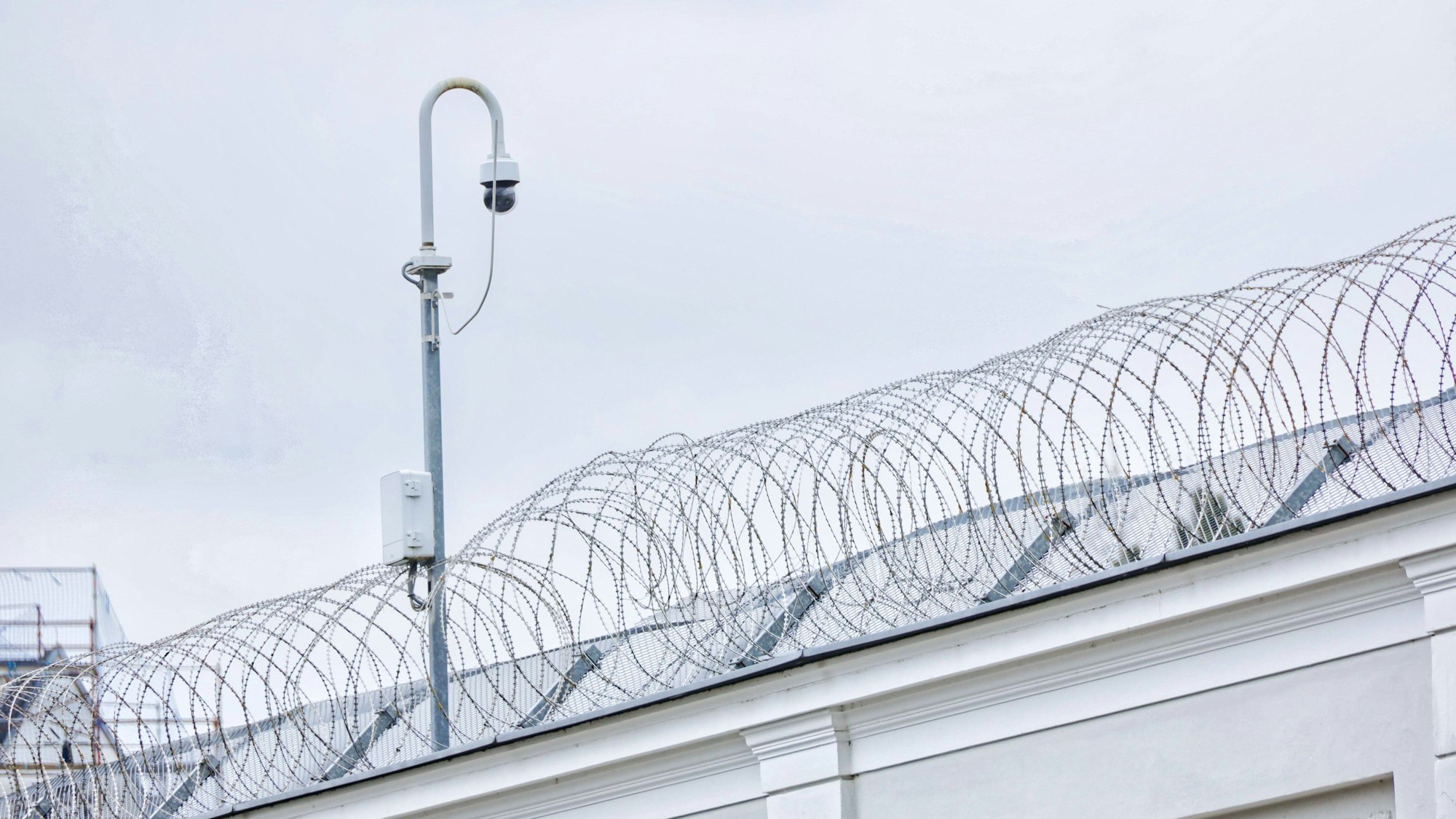 Gefängnismauer mit Stacheldraht und Kamera