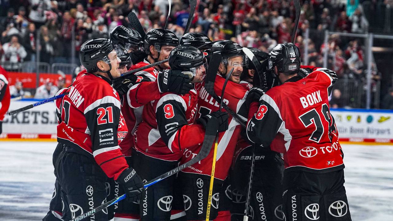 Die Spieler der Kölner Haie jubeln und umarmen sich auf dem Eis.