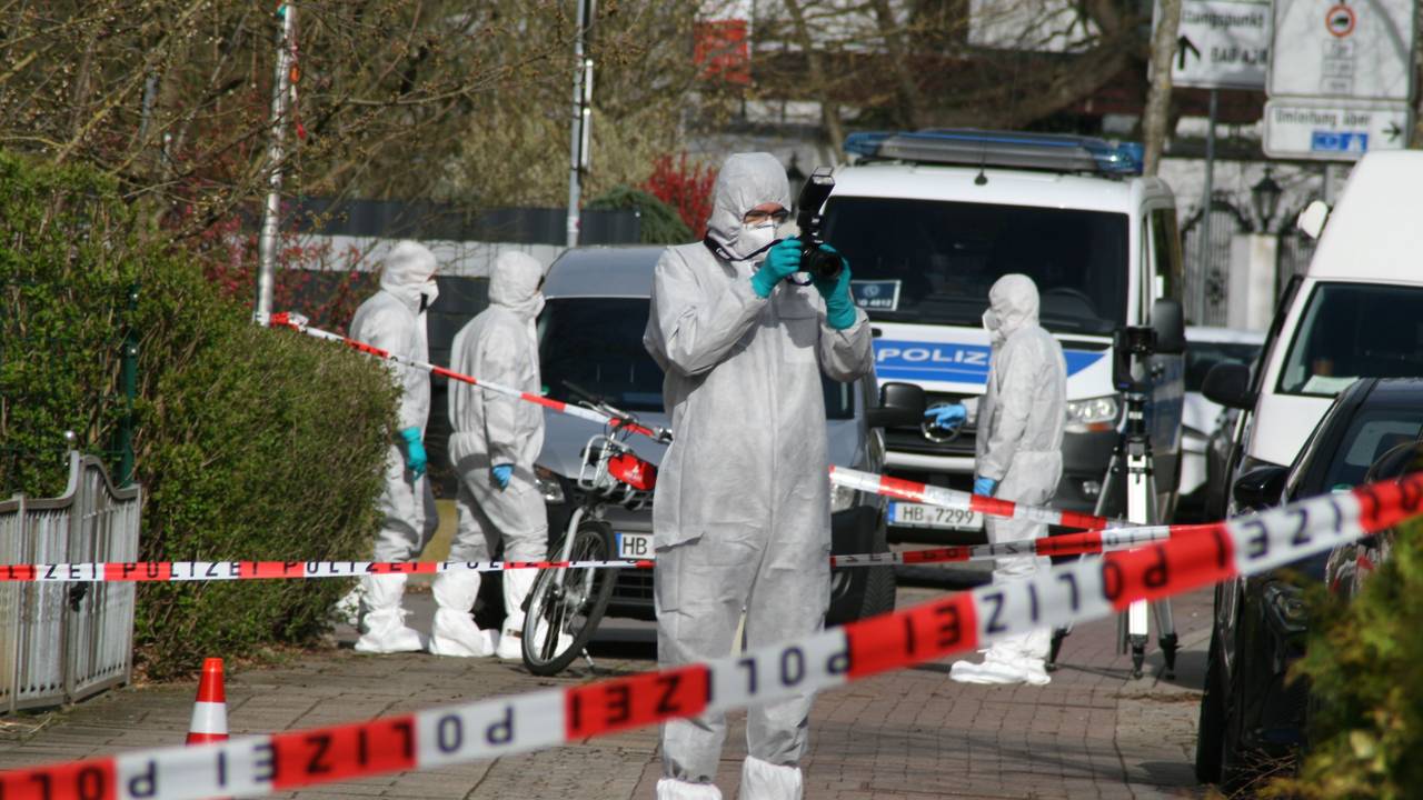Vier Personen ind Schutzanzügen sind an dem Tatort, der mit Polizeiflatterband abgesperrt ist.