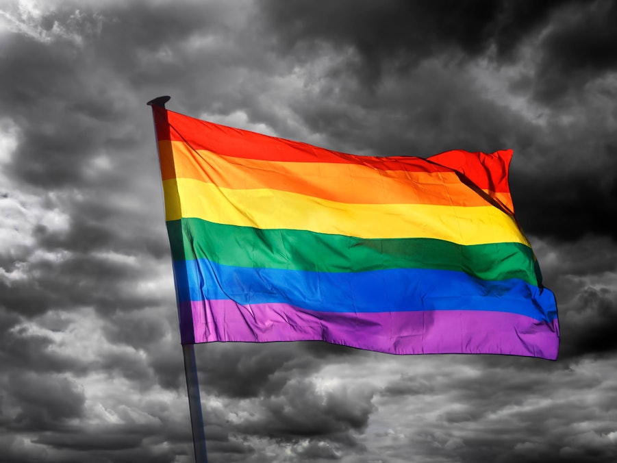 Wehende Regenbogenflagge vor dunklem Himmel