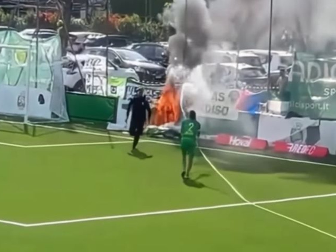 Ein Spieler löscht mit einem Schlauch ein Feuer hinter dem Tor.