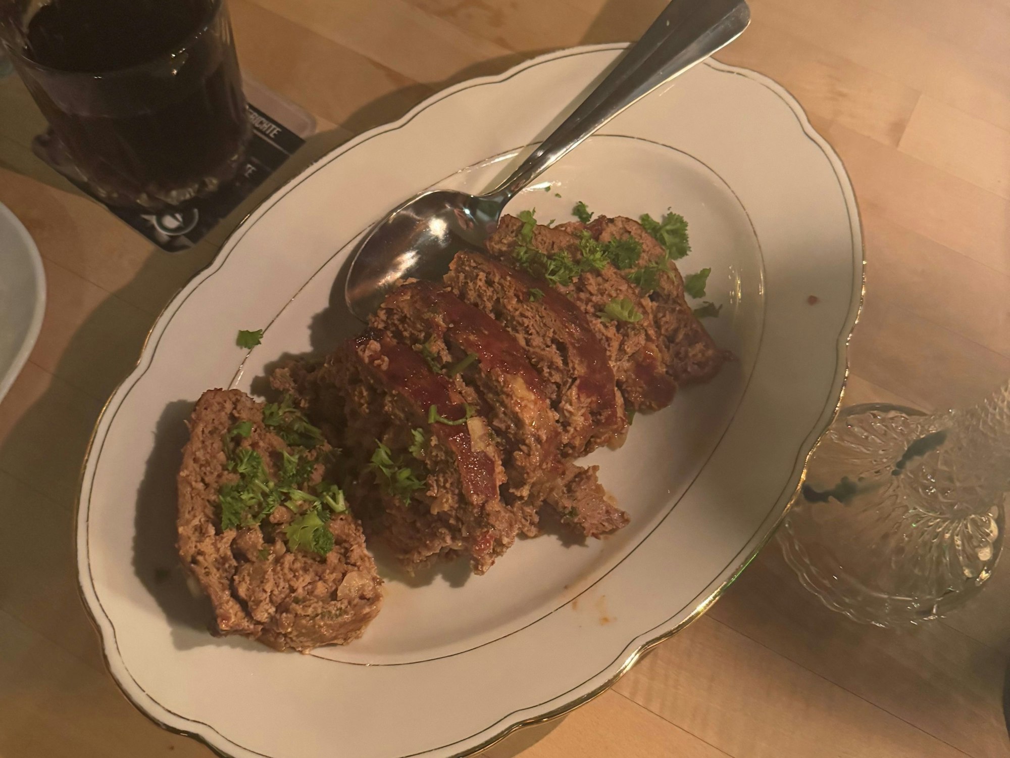 Ein Hackbraten liegt aufgeschnitten auf einer weißen Porzellan-Servierplatte.