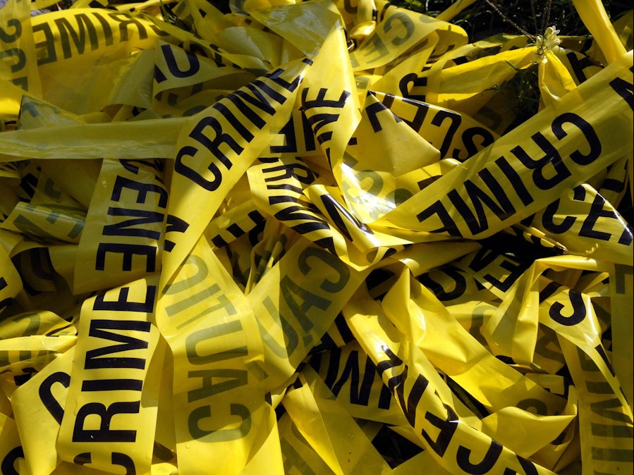 Gelbes Absperrband „Crime Scene“ auf einem Haufen