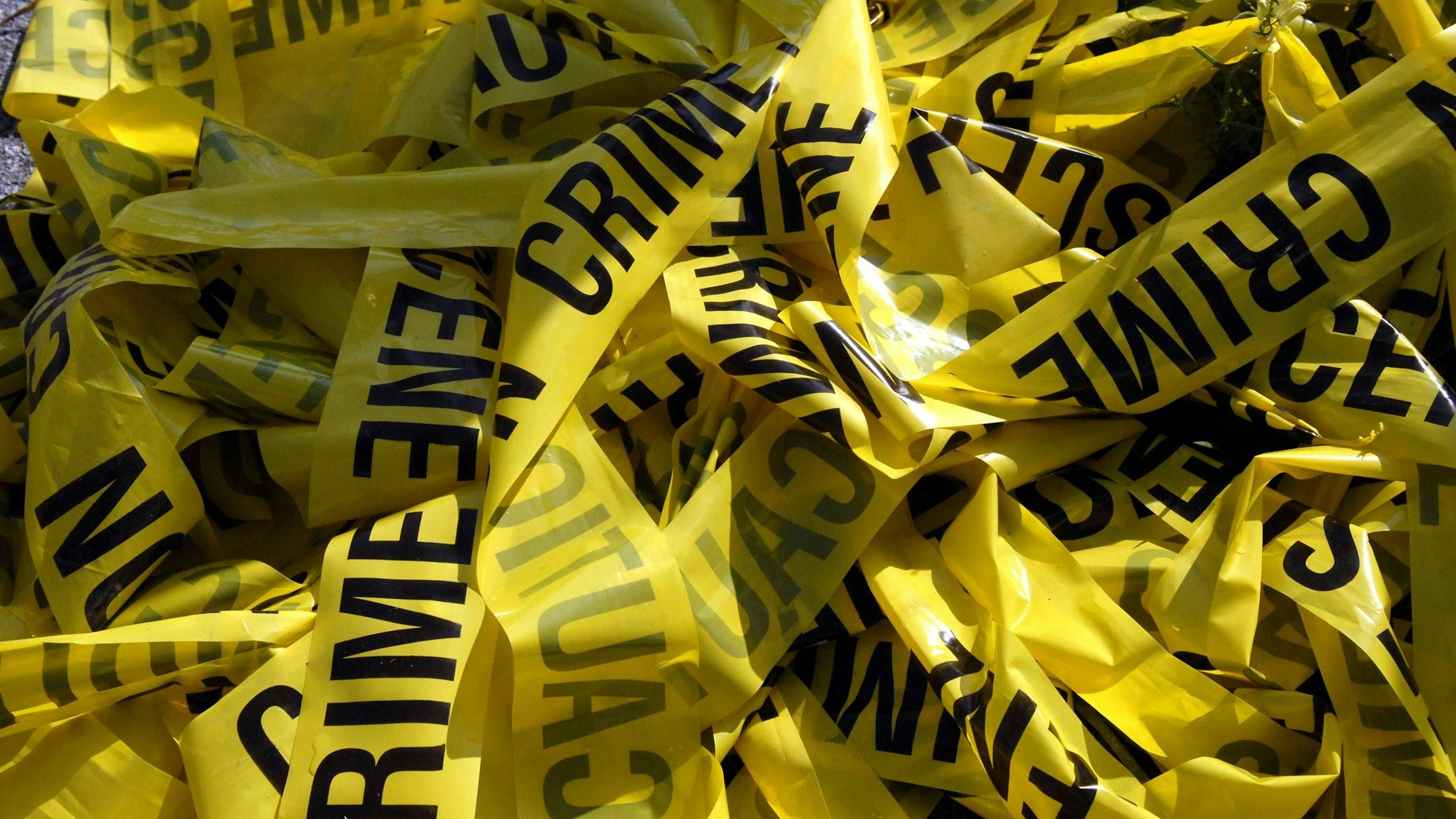 Gelbes Absperrband „Crime Scene“ auf einem Haufen